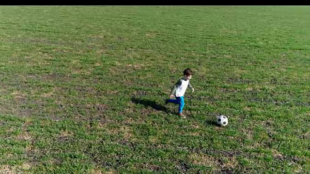 活跃的男孩在绿地上踢足球，无人机拍摄的画面视频下载