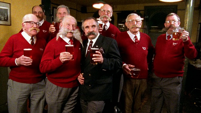一群穿着一模一样的红毛衣的中年男子举杯互敬啤酒视频素材