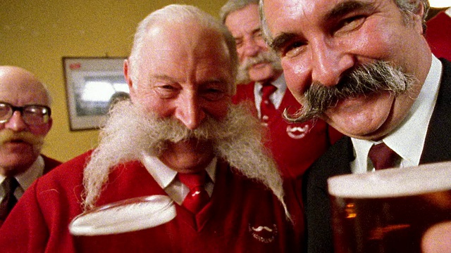 特写两位留着精致小胡子的高级男子，他们正在举杯庆祝啤酒视频素材