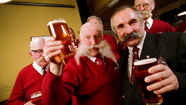 中镜头摄影车拍摄的是穿着红毛衣的高级男子，他们一边喝着啤酒一边聊天视频素材