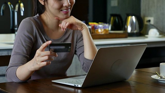 年轻女子用信用卡和笔记本电脑在家在线支付账单视频素材