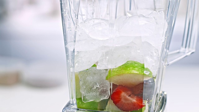 在搅拌机罐中向水果中加入冰块视频下载