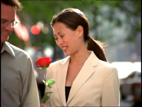 男人递给女人一朵长茎玫瑰后，女人看起来很高兴。视频素材