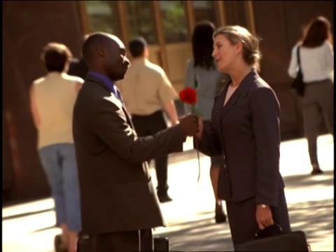 女人在男人送给她玫瑰后亲吻他的脸颊。视频素材