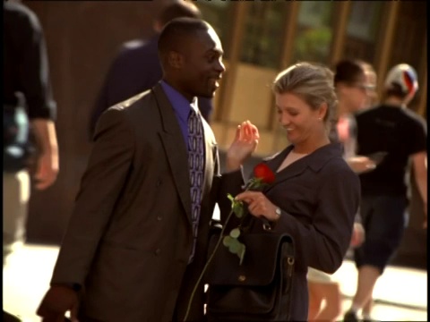 女人在男人送给她玫瑰后亲吻他的脸颊。视频素材