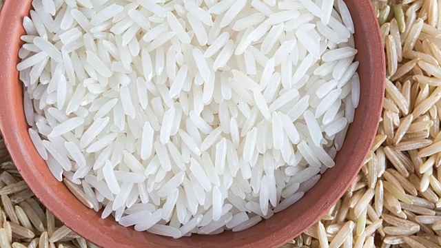 小盘里的白米与背景里的糙米相比。重要的碳水化合物食品视频下载