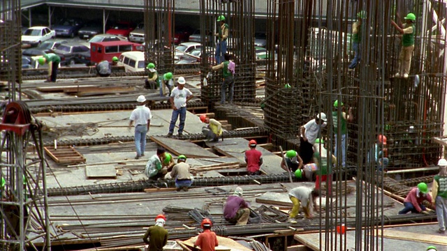中镜头延时拍摄工人在建筑工地周围移动视频素材