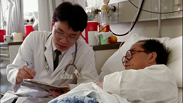 中拍年輕醫生在床上與病人討論病例/香港視頻素材
