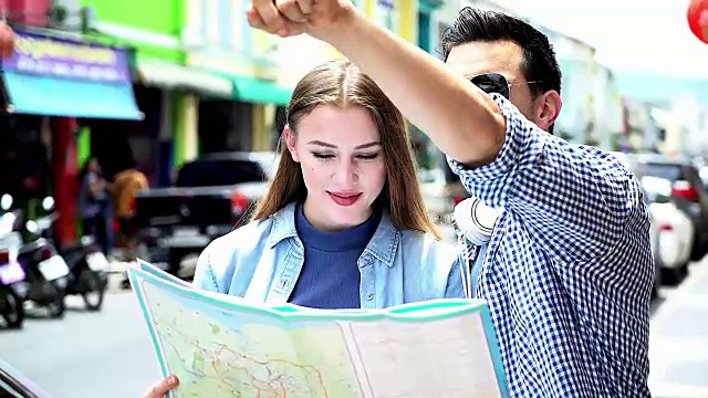 微笑的情侣戴着太阳镜与地图在城市夏季度假，约会和旅游的概念。视频下载