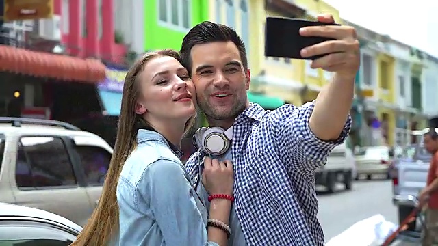 一对快乐的游客夫妇在自拍后看着相机上的照片。视频下载