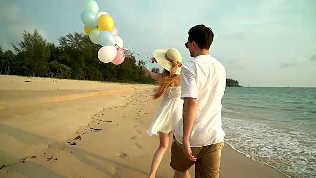一对情侣在海滩上散步。年轻幸福的跨种族情侣走在海滩上微笑着彼此拥抱。亚洲女人，白人男人。视频下载