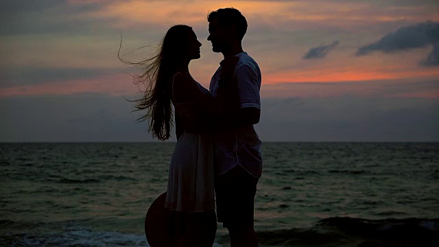 4K:情侣在日落海滩上的剪影场景，关于爱情和关系的美丽背景，男人和女人视频下载