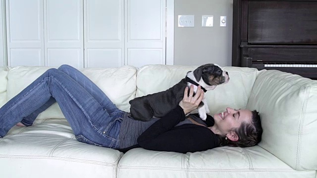 一个年轻女子躺在沙发上抚摸着她的狗视频下载