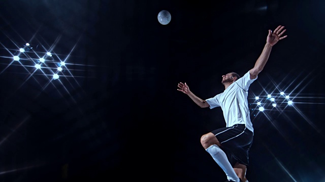 SLO MO LD穿着白色球衣在黑色背景下用剪刀式踢球的男性足球运动员视频下载