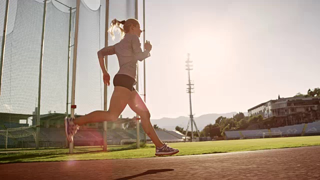 SLO MO TS女运动员在阳光体育馆的跑道上跑步视频下载
