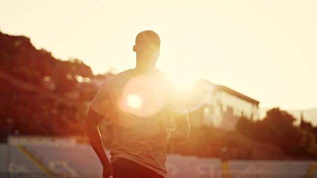SLO MO DS非裔美国人在夕阳下在体育场中奔跑视频下载