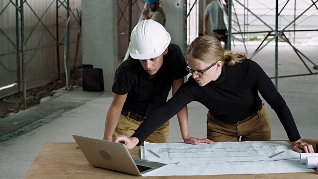 女建筑师和女施工协调员在施工现场检查平面图视频下载