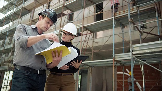 男建筑师和女建筑师站在建筑外面，检查数字平板电脑上的平面图视频素材