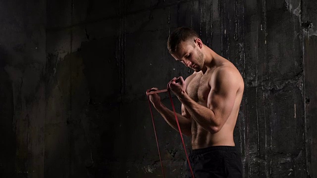肌肉男模特用橡皮筋做运动的侧面图视频素材
