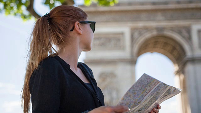 一位妇女站在著名的凯旋门前看巴黎地图视频素材
