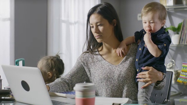 中等平移拍摄沮丧的母亲与孩子在桌子上工作/雪松山，犹他州，美国视频下载