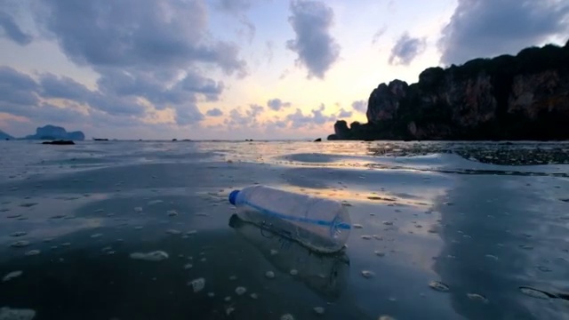 4k:环境污染，夕阳下海上的瓶子视频下载