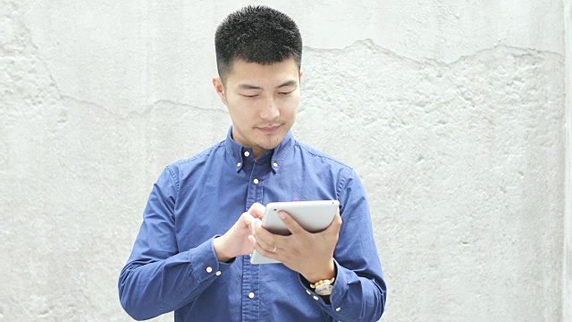 年轻的亚洲男子使用数字平板电脑视频下载