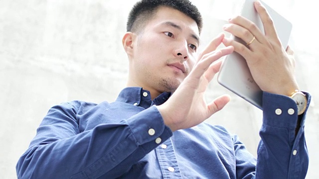 年轻的亚洲男子使用数字平板电脑视频下载