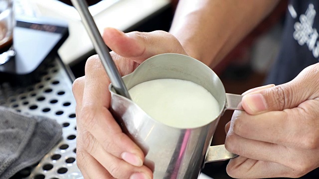咖啡师用蒸汽棒蒸牛奶来拿铁或卡布奇诺视频下载