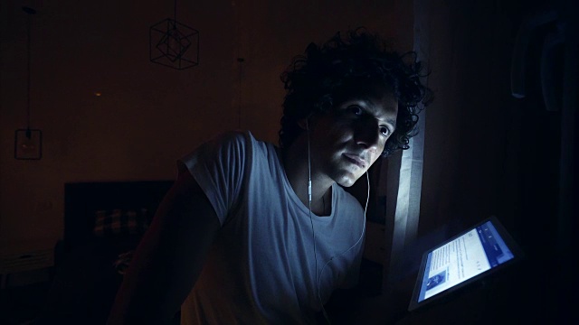一个年轻人在深夜使用平板电脑。视频素材