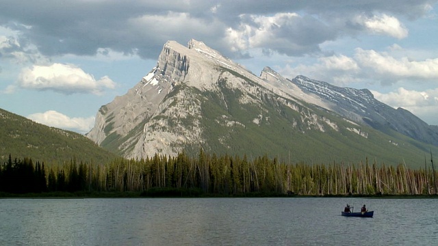 两个人在加拿大亚伯达省班夫国家公园伦德尔山附近的朱砂湖上划独木舟视频素材