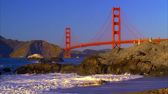 快速运动，WS，金门大桥，海浪粉碎的岩石在贝克海滩前景，旧金山，加利福尼亚，美国视频素材