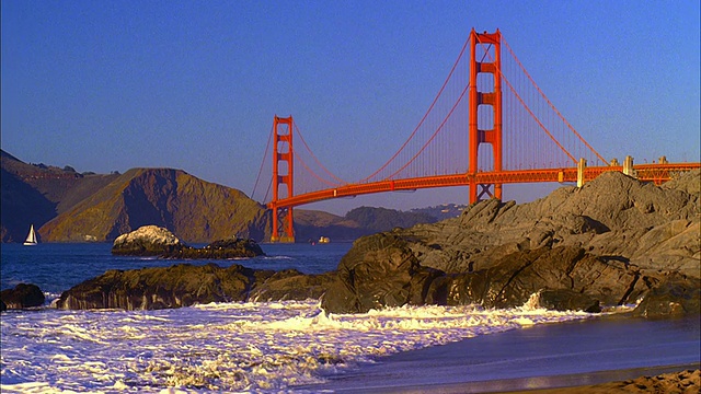 WS，金门大桥，海浪粉碎在贝克海滩的岩石在前景，旧金山，加利福尼亚，美国视频素材