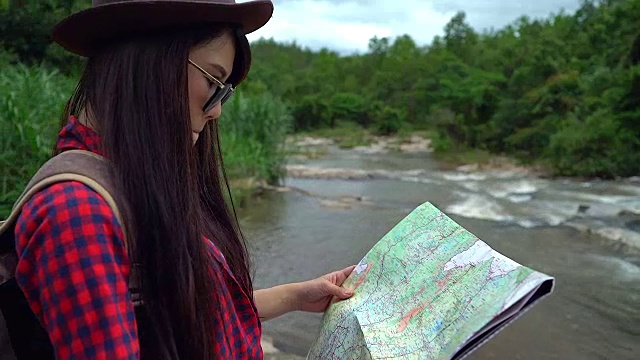 年轻女性在冒险旅行中看地图。视频下载
