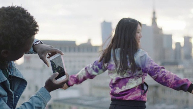 快乐的年轻亚洲女人在屋顶上摆姿势与摄影师与智能手机视频素材