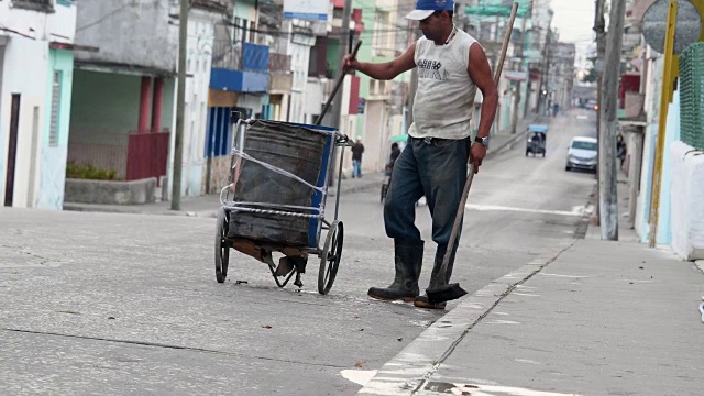 古巴，圣克拉拉:一名年轻人正在清扫街道。他的衬衫上写着“喇嘛萨巴萨尼”视频下载