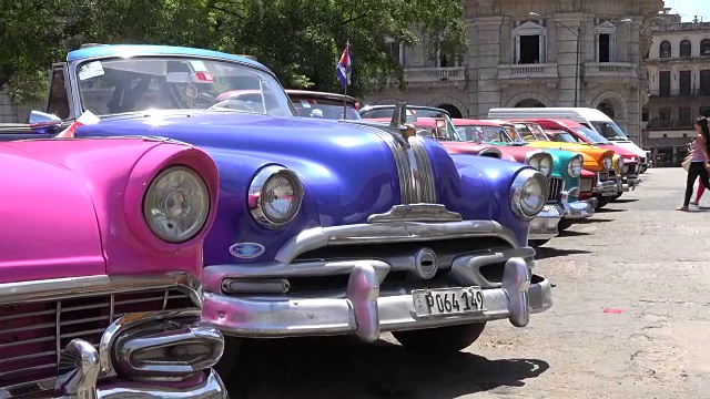古巴，哈瓦那:在古巴首都，老式的美国汽车作为旅游出租车工作。它们是用鲜艳的颜色画的。视频下载