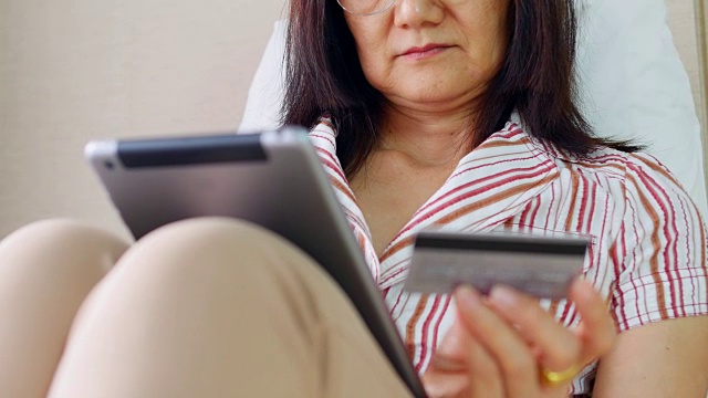 成熟的女人用平板电脑刷信用卡视频素材