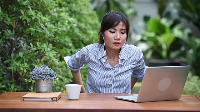一位亚洲年轻女子在花园里用笔记本上网购物视频素材