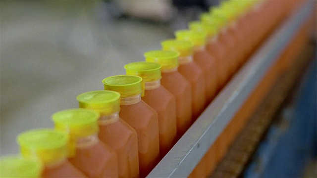 选择性聚焦近锅密封胡萝卜汁瓶堆积在传送带在果汁工厂视频下载