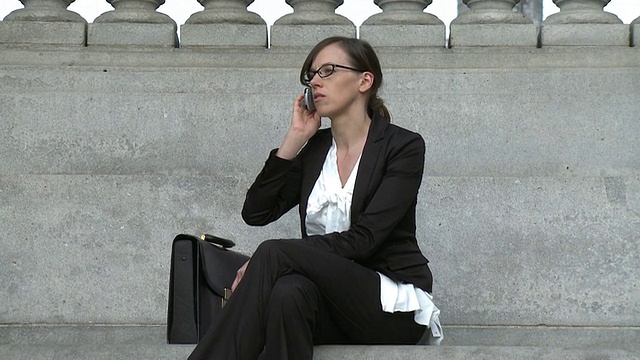 美国纽约，纽约市，商务女性坐在办公大楼外打电话视频素材