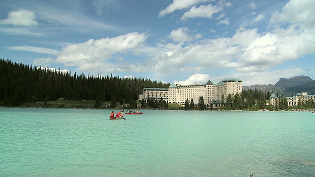 加拿大阿尔伯塔省班夫国家公园，人们在路易斯湖上泛舟，背景是路易斯城堡湖酒店视频下载