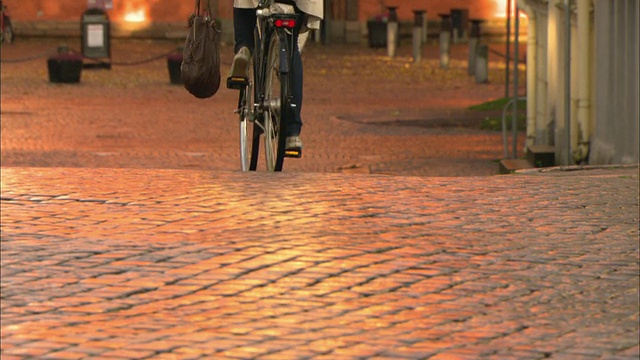 在瑞典瓦克斯乔的鹅卵石路上骑自行车的女子视频素材