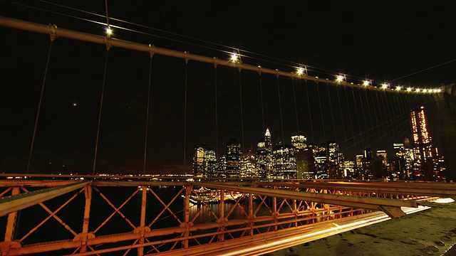夜间布鲁克林大桥上的交通，背景中的城市景观/美国纽约州纽约市视频素材