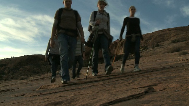 沿着岩石山坡行走的徒步旅行者视频素材