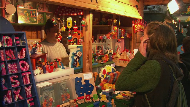 在英国萨默塞特的巴斯圣诞市场购买彩色木制玩具的女士视频下载