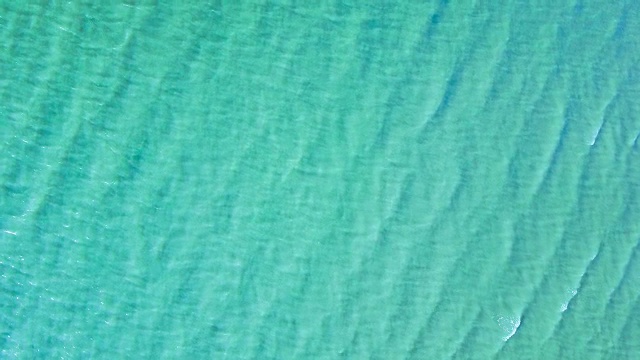 无人机拍摄的海浪到达海岸的画面。锁定拍摄的海浪创建一个纹理从白色的海洋泡沫。视频是从头顶的角度拍摄的视频下载