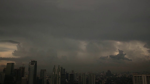 在印度尼西亚的雅加达，乌云笼罩在灰色的天空和摩天大楼上视频下载