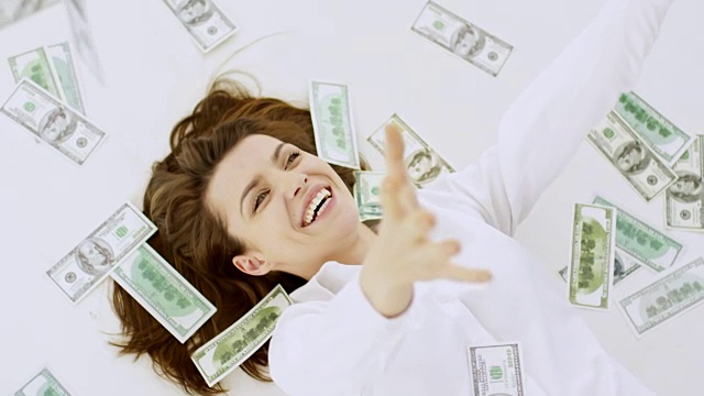 钱落在躺在地板上的女人身上视频素材