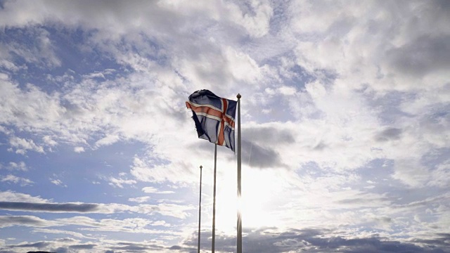 冰岛国旗在日落时对天空和太阳挥舞- 4K视频-旅游目的地北欧国家的概念视频素材
